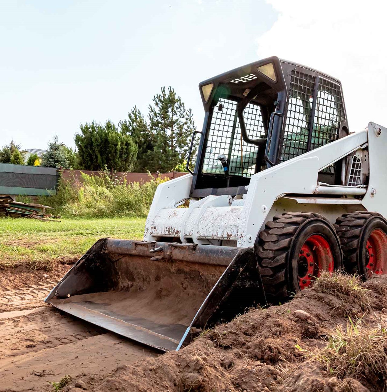 Chargeur sur roues en train de niveler le sol grâce aux lames de bulldozer.