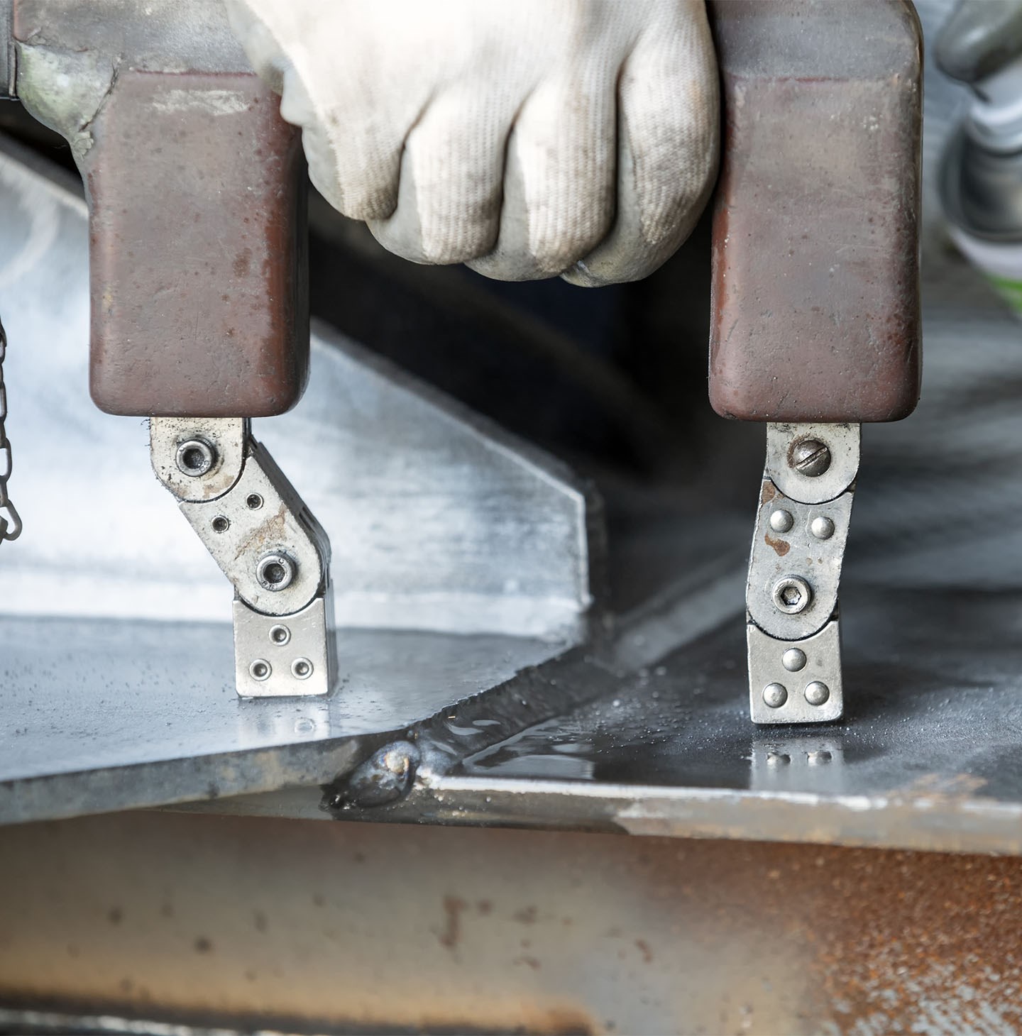 Une main tient un outil pour tester les particules magnétiques entre deux plaques de métal.